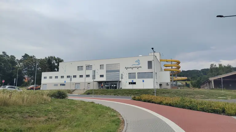 Bílá budova aquacentra se žlutým tobogánem ve Šternberku