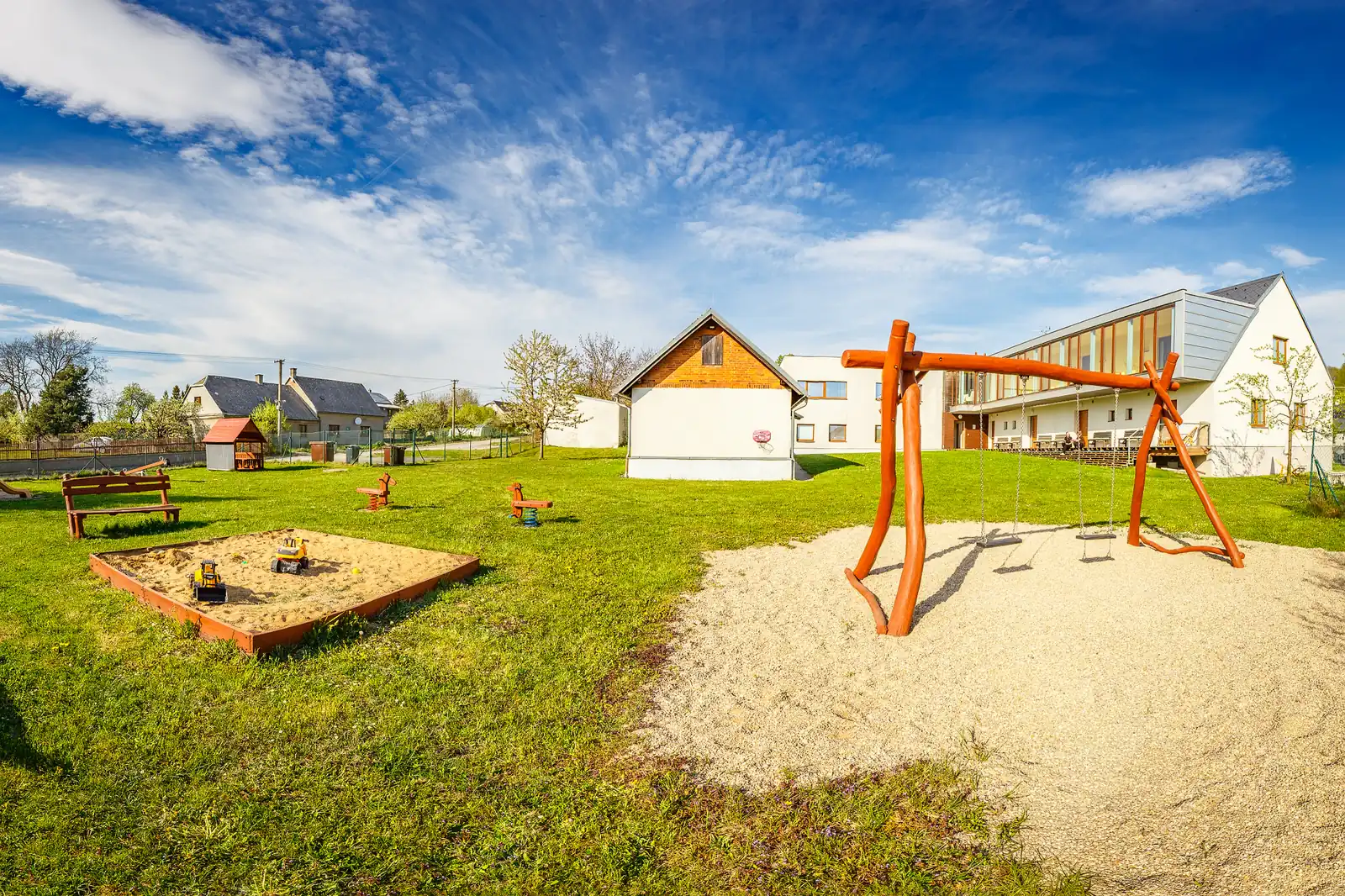 Houpačky, dětské herní prvky a trávník na zahradě